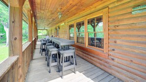 A wooden deck with a long table and bar stools, a 'Welcome' sign, and a view of greenery. - 4 Mi to Grandfather Mtn! Family-friendly Cabin (Newland)