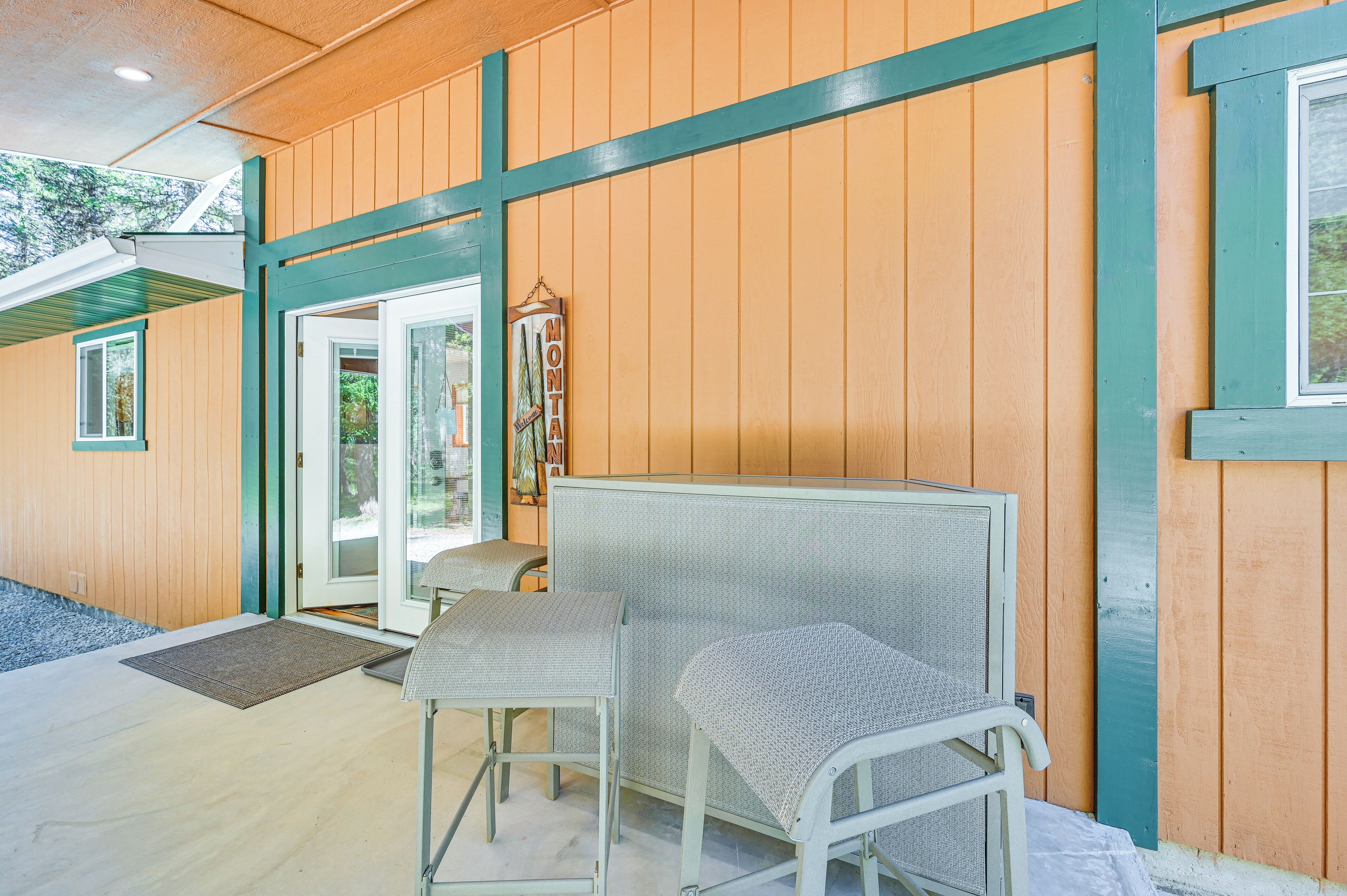 A wooden exterior with a green-framed door and a small seating area with two chairs.