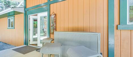 A wooden exterior with a green-framed door and a small seating area with two chairs.