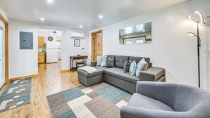 A modern living room with a sectional sofa, a gray armchair, and a wooden floor. - Peaceful Eureka Getaway - 1 Mi to Glen Lake! (Eureka)