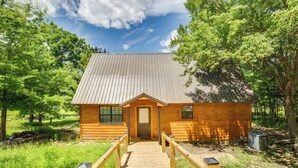 A wooden cabin with a metal roof, a wooden front door, and a wooden walkway leading to it. - Cabin on Lake Raymond Gary w/ Dock, Grill & Views! (Fort Towson)