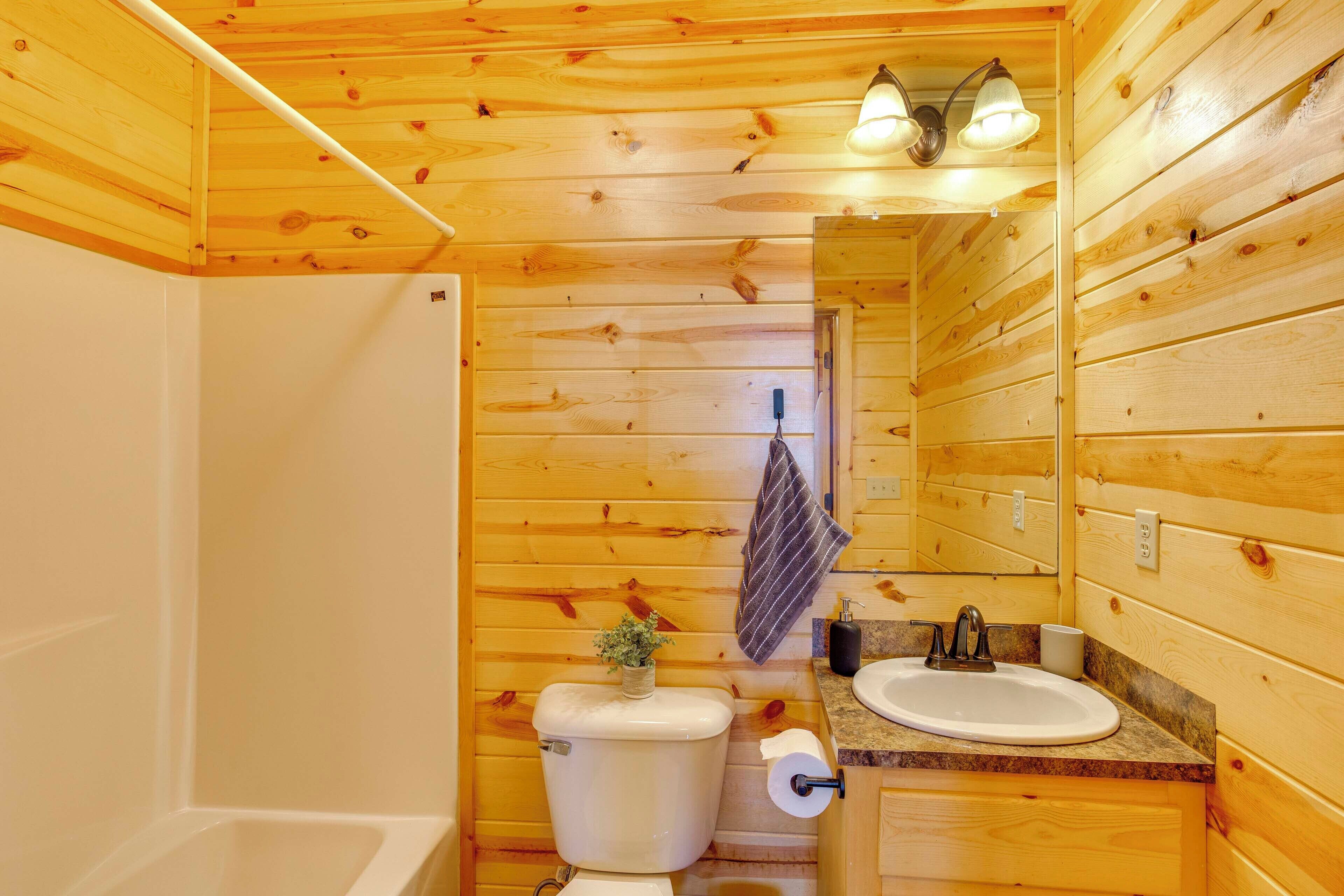 Une salle de bain aux murs lambrissés, équipée de toilettes, d’un lavabo et d’une douche.