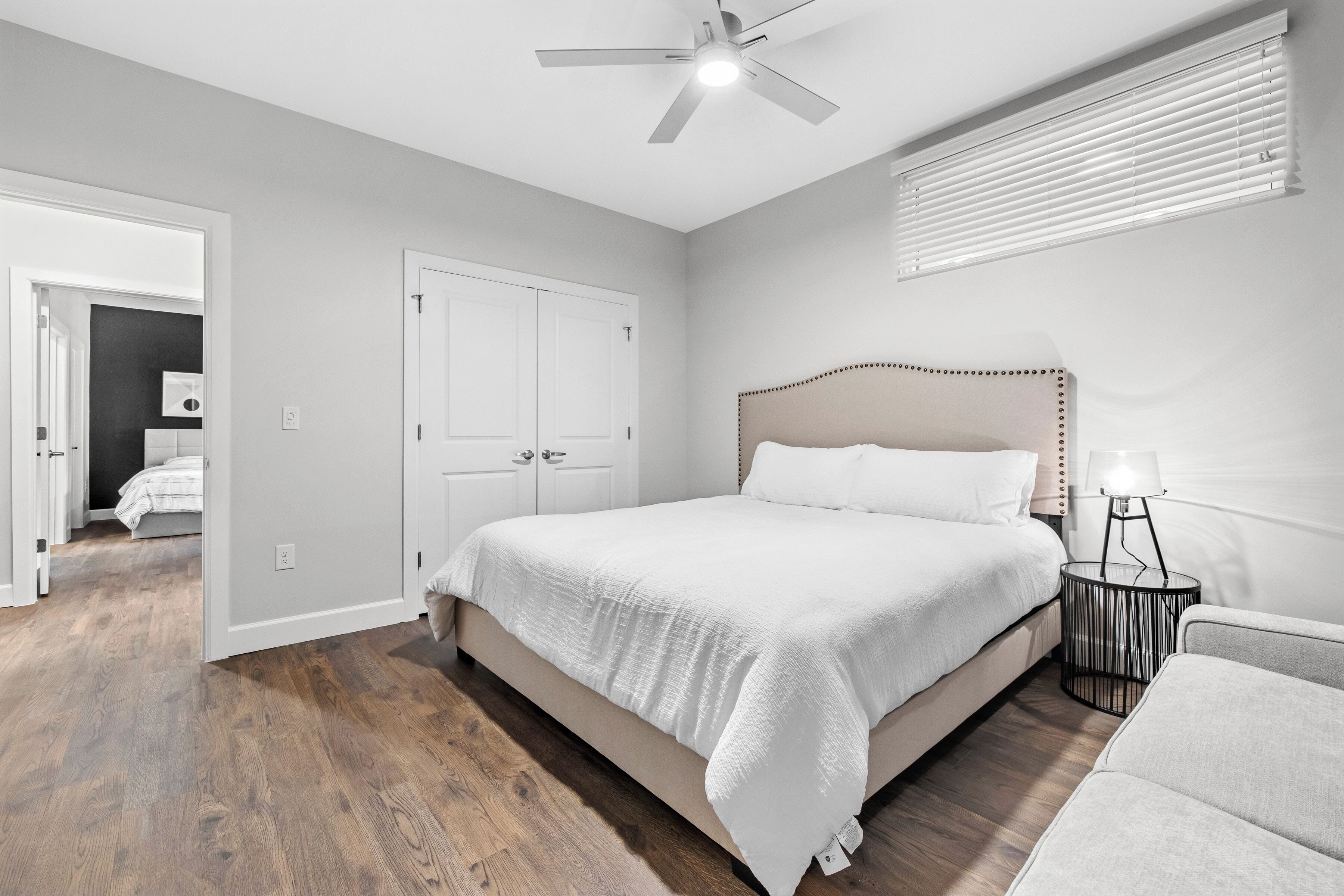 Una camera da letto con un letto grande, una ventola a soffitto, una lampada da comodino e una porta che dà su un'altra stanza.