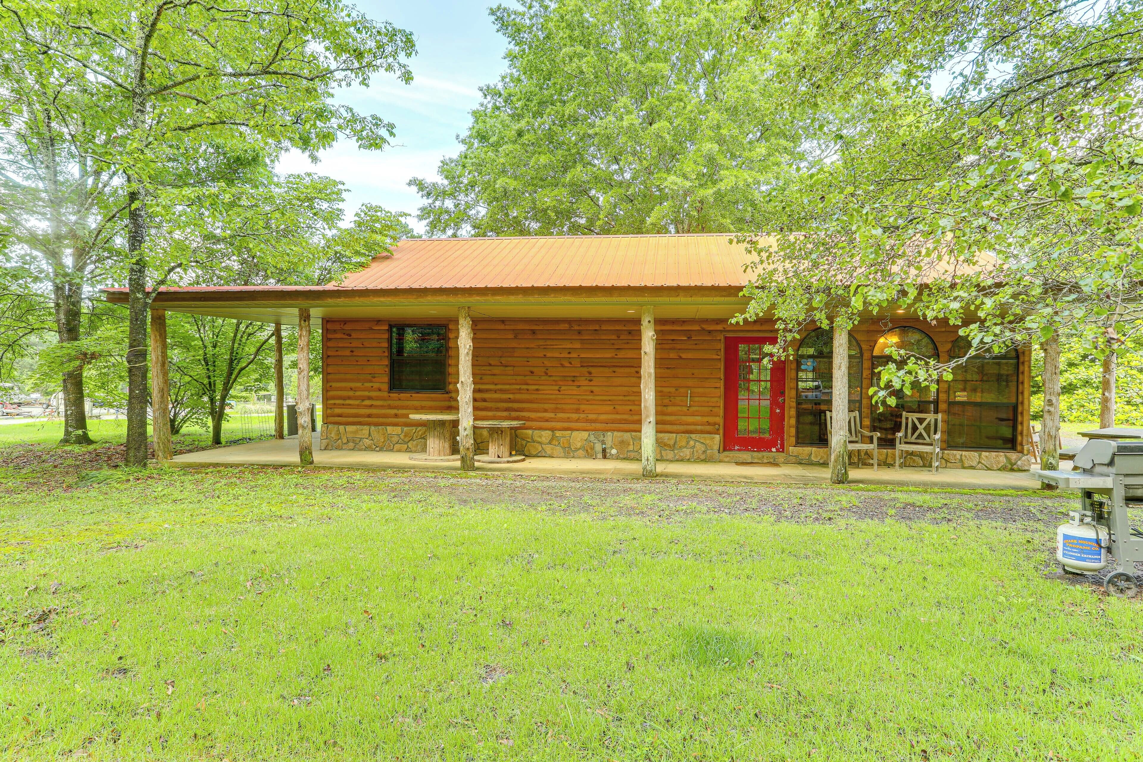 Un rustico chalet con una porta rossa, pareti in legno e un portico coperto.
