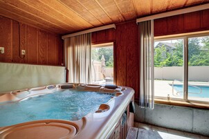 Un jacuzzi con interior de madera, una ventana con cortinas y vista a un patio trasero con piscina.