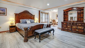 Une chambre à coucher avec un lit en bois, un banc, une commode et un ventilateur de plafond.
