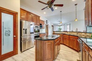 A kitchen with wooden cabinets, stainless steel appliances, a ceiling fan, and pendant lighting. - Junction City Home w/ Hot Tub - Near Milford Lake! (Junction City)