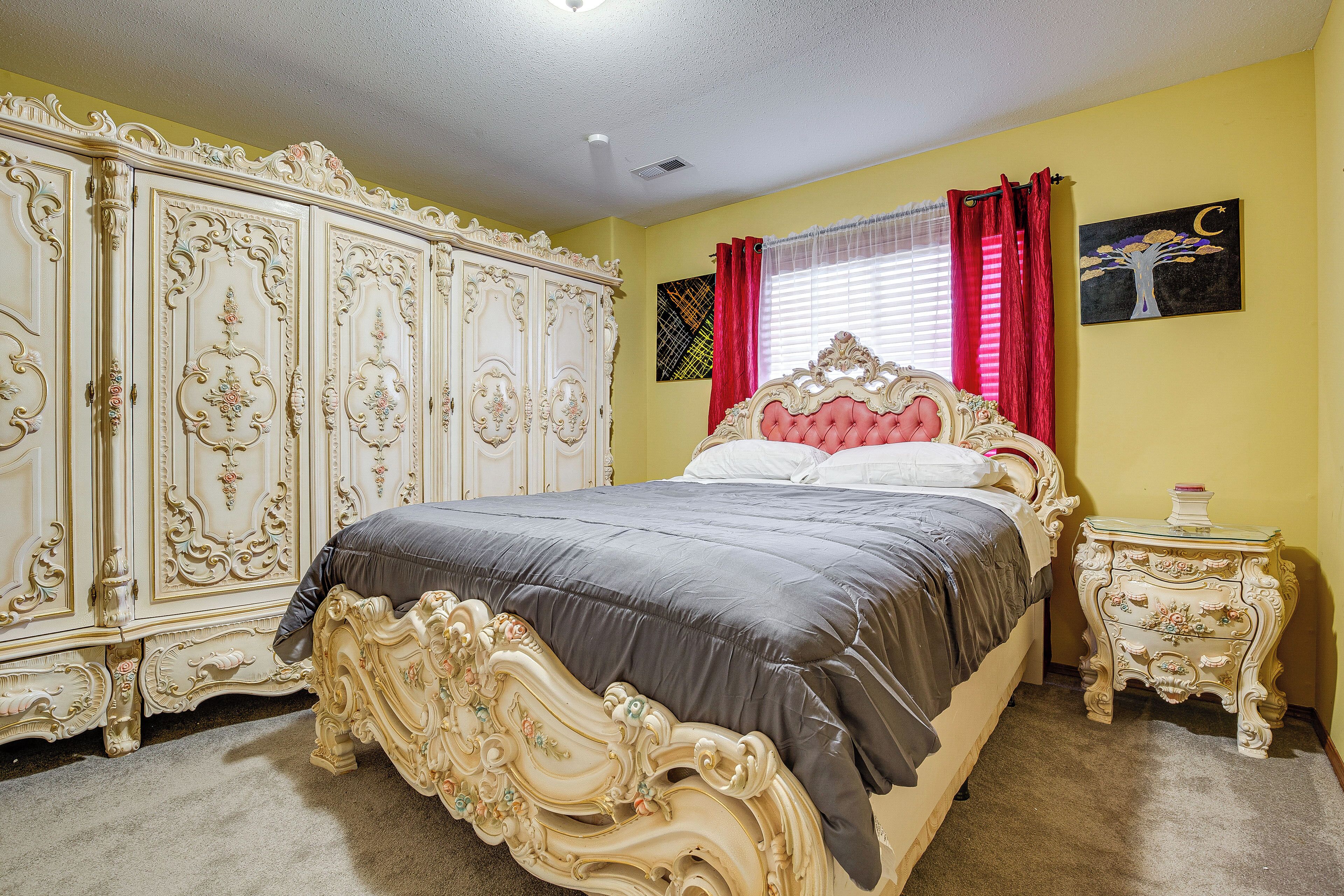 A bedroom with a large ornate bed, a matching dresser, and a nightstand.