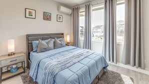 A bedroom with a bed, nightstands, a lamp, and a window with curtains.