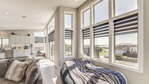 A spacious living room with a large window, a sofa, and a view of the backyard.