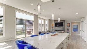 A spacious kitchen with a large island, blue bar stools, and a view of the outdoors.