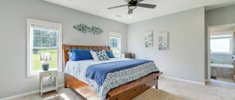 A bedroom with a bed, a nightstand, a ceiling fan, and a window.