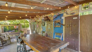 A rustic wooden table with bar stools, a blue door with a 'Good' sign, and a 'Welcome outdoors' sign.