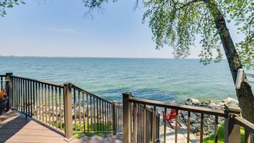 A wooden deck with a metal railing overlooking a body of water.