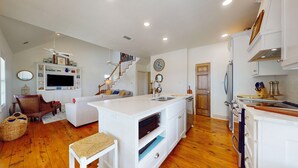 A spacious living area with a large TV, a dining table, and a kitchen with a built-in oven. - Gordeaux's Place: 3  BR, 2  BA House in Crystal Beach, Sleeps 8 (Bolivar Peninsula)