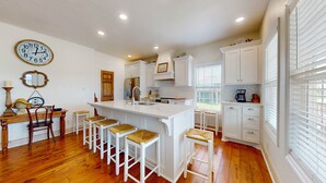 A kitchen with a central island, white cabinetry, wooden flooring, and a clock on the wall. - Gordeaux's Place: 3  BR, 2  BA House in Crystal Beach, Sleeps 8 (Bolivar Peninsula)