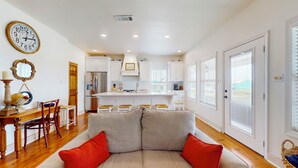 A modern kitchen with white cabinets, a stainless steel refrigerator, and a dining area with a wooden table and chairs. - Gordeaux's Place: 3  BR, 2  BA House in Crystal Beach, Sleeps 8 (Bolivar Peninsula)