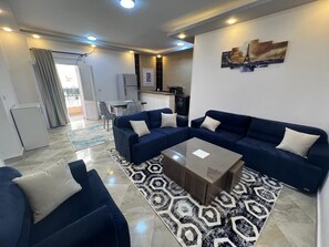 A modern living room with a sofa set, a coffee table, and a patterned rug. - Comfy One-Bedroom Apartment (Hurghada)