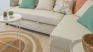 A modern living room with a sofa, a small round table with a plant, and a woven rug. - Villa Sierra Sea Views Quesada with private swimming pool (Ciudad Quesada)