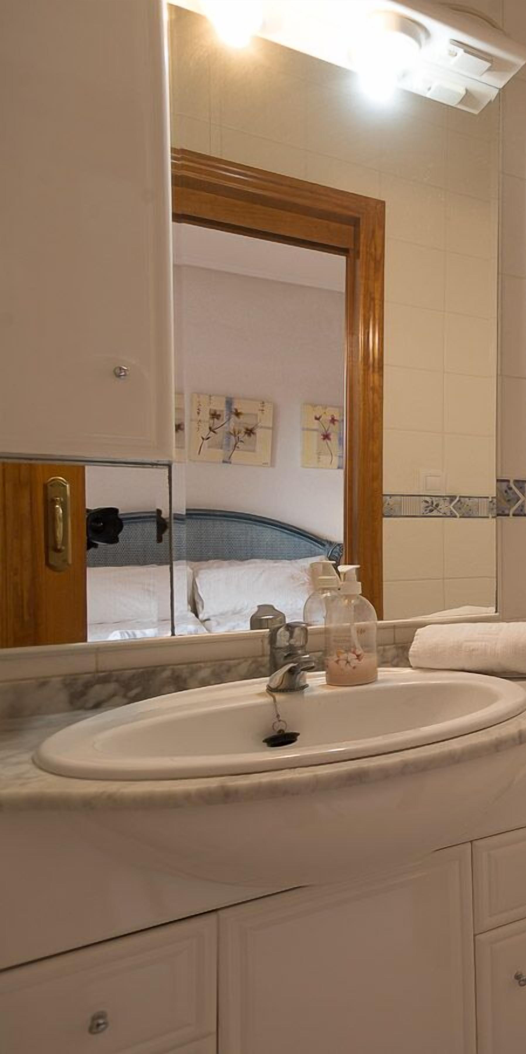 Ein Badezimmer mit einem weißen Waschbecken, einem Spiegel und einer Holztür.
