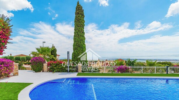 A swimming pool with a clear blue sky, surrounded by well-maintained greenery and a tall tree. - Villa Sierra Sea Views Quesada with private swimming pool (Ciudad Quesada)