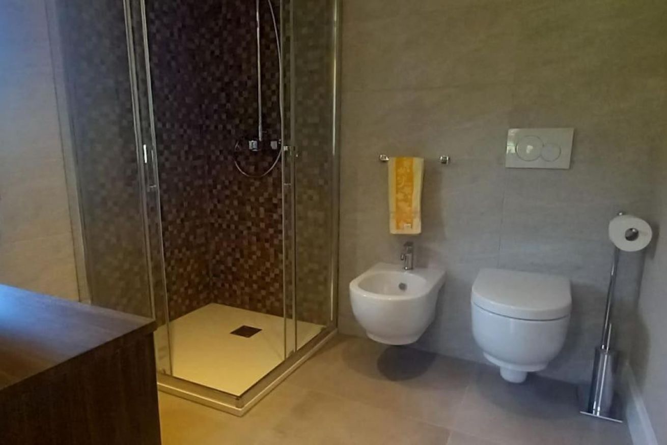 Un bagno con cabina doccia in vetro, un bidet, un water e un portasciugamani.