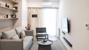 A modern living room with a sofa, a coffee table, a TV, and a chair. - Super luxury SUITE with Gym (Athina)