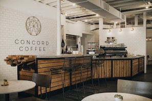 Ein modernes Café-Interieur mit Barbereich, Sitzgelegenheiten und einer sichtbaren Kaffeemaschine.