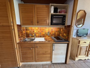 A compact kitchen with wooden cabinets, a microwave, and a sink.