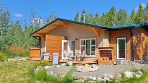 A wooden cabin with a porch, outdoor seating, and a fireplace. - Yukon Hot Springs Villa #33 (Whitehorse)