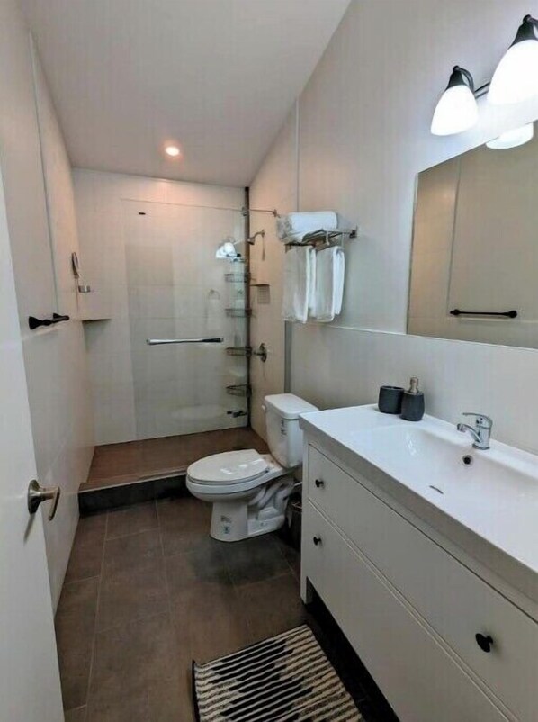 Une petite salle de bain comprenant des toilettes, une douche et un meuble-lavabo avec un miroir.
