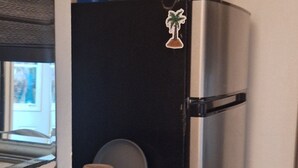Eine kleine Küchenzeile mit Kühlschrank, Mikrowelle und einer Arbeitsfläche.