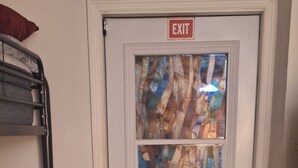 Eine weiße Tür mit Ausgangsschild, einem Glasfenster und einem Hochbett links.