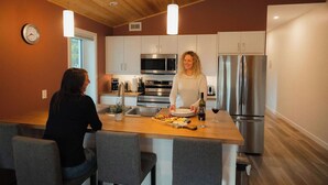 A modern kitchen with stainless steel appliances, a wooden island, and a clock on the wall.