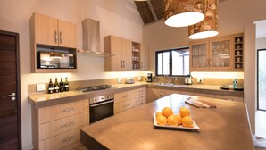 Eine moderne Küche mit Holzschränken, einer zentralen Kochinsel mit Orangen und einer hängenden Leuchte.