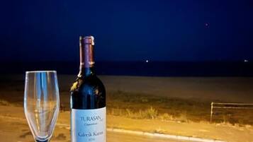 Une bouteille de vin Turasan et un verre vide sur une table à l’extérieur, la nuit.