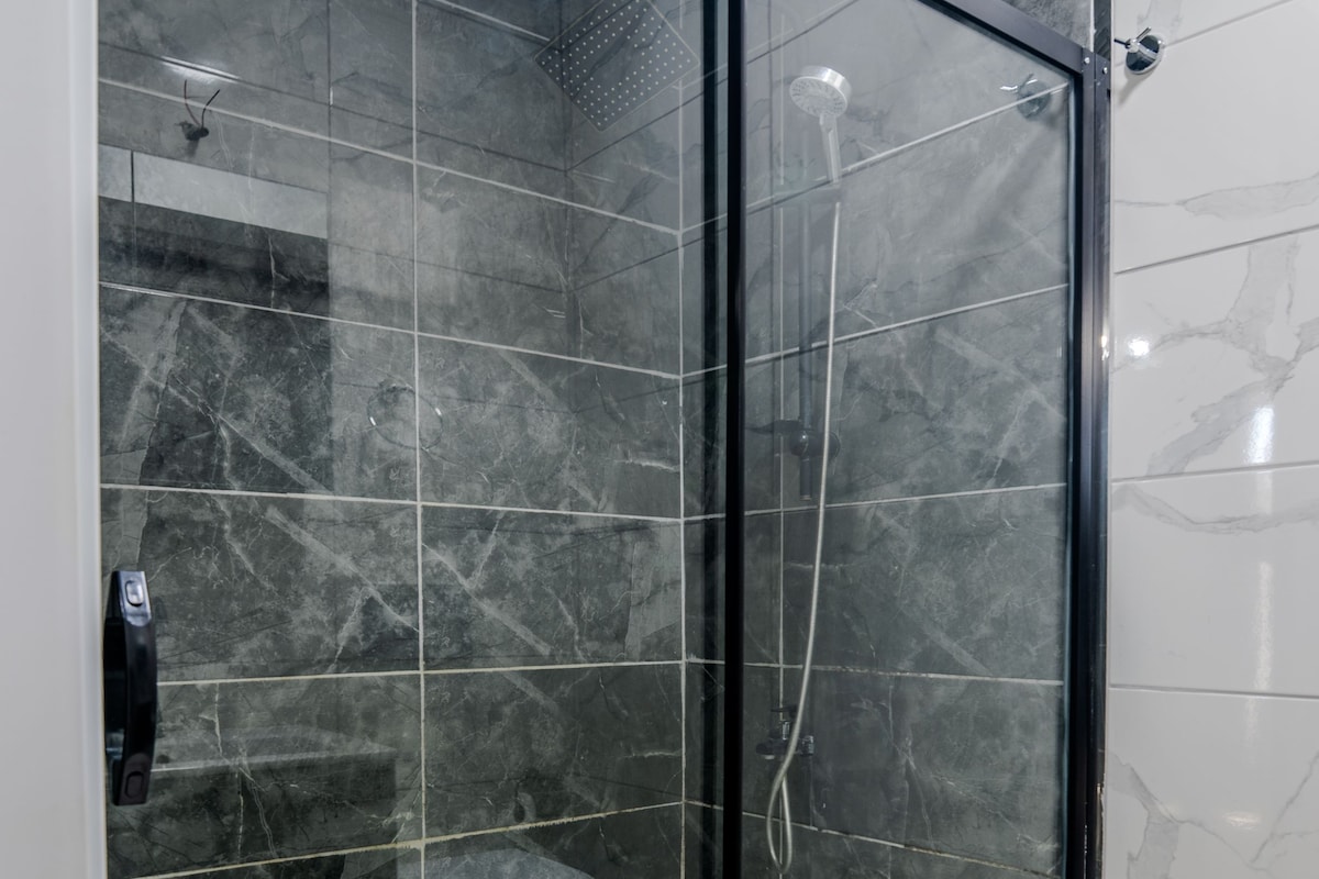 A glass-enclosed shower with a tiled floor and walls.