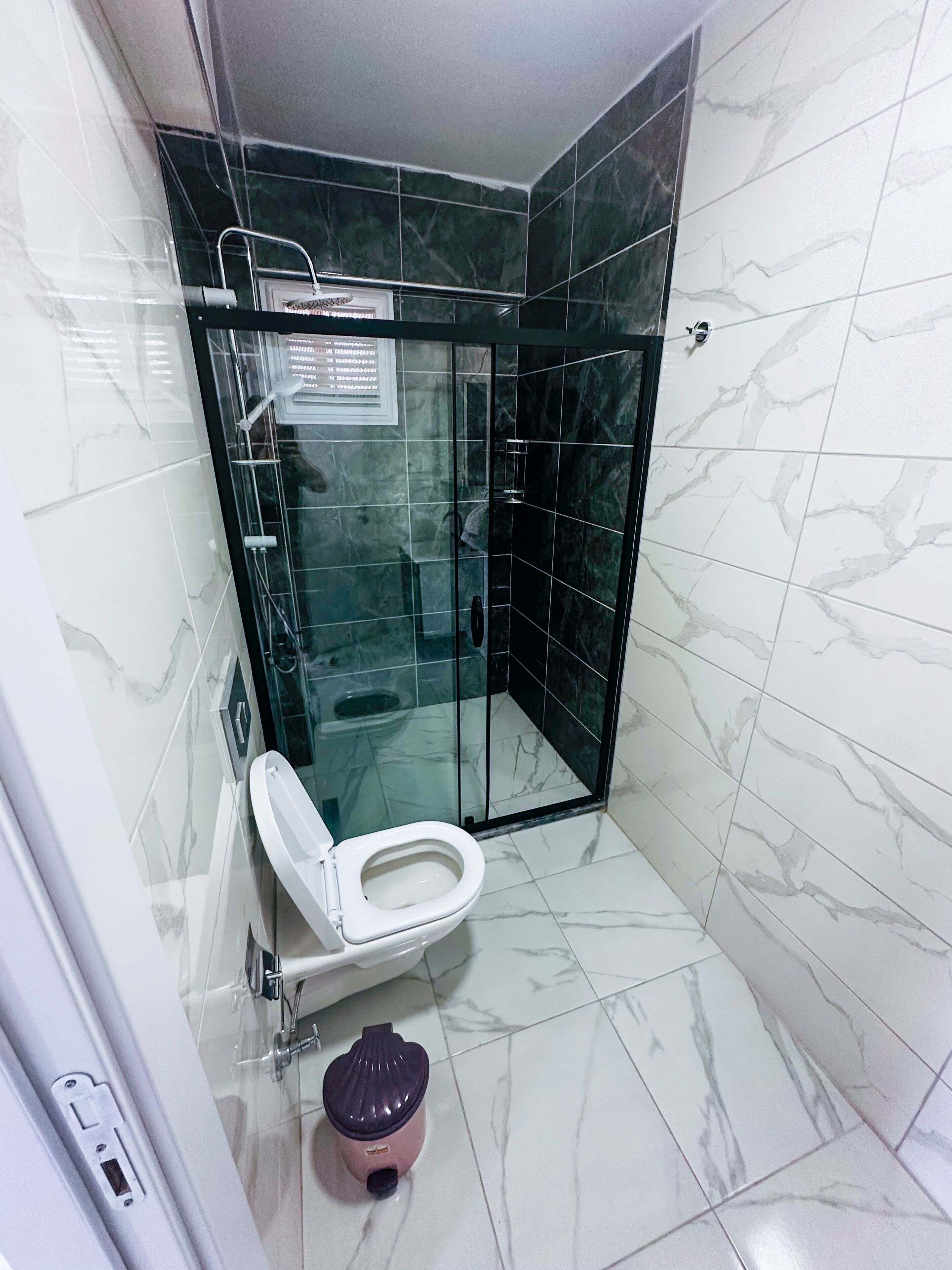 A bathroom with a glass-enclosed shower, a toilet, and a bidet.