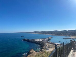 Vista costera con muelle, barcos y cielo despejado.
