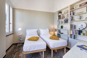 Une chambre avec deux lits, une bibliothèque et une fenêtre.