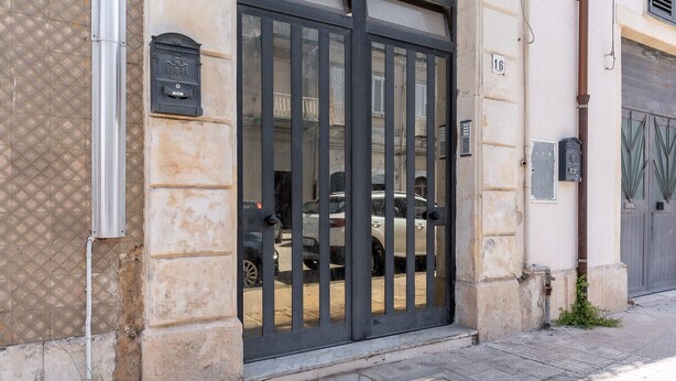 Una entrada de edificio con una reja de metal, un buzón y una placa con un número.
