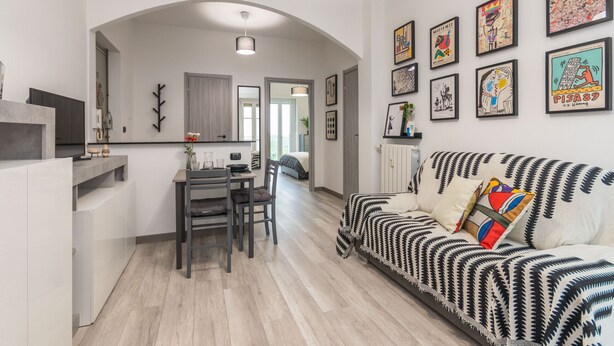 A modern living room with a sofa, a dining table, and chairs. There are framed pictures on the wall. - Il Rifugio del Viaggiatore by Wonderful Italy (Torino)