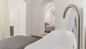 Une chambre à coucher moderne avec une baignoire blanche, un canapé gris et un tapis rouge.
