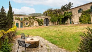 A stone building with a courtyard, outdoor seating, and greenery. - Dependance a Baglio il Corvo by Wonderful Italy (Gangi)