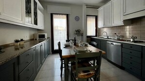 Une cuisine moderne avec des meubles blancs, une table à manger en bois pour quatre personnes et un lave-vaisselle.