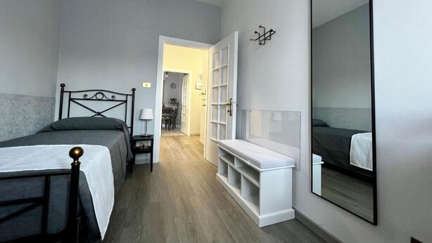 Une chambre avec deux lits, un grand miroir et un banc intégré.