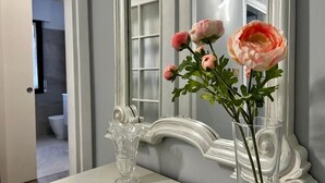 Un meuble-lavabo de salle de bain avec un miroir, un vase transparent rempli de fleurs et un pichet en verre décoratif.
