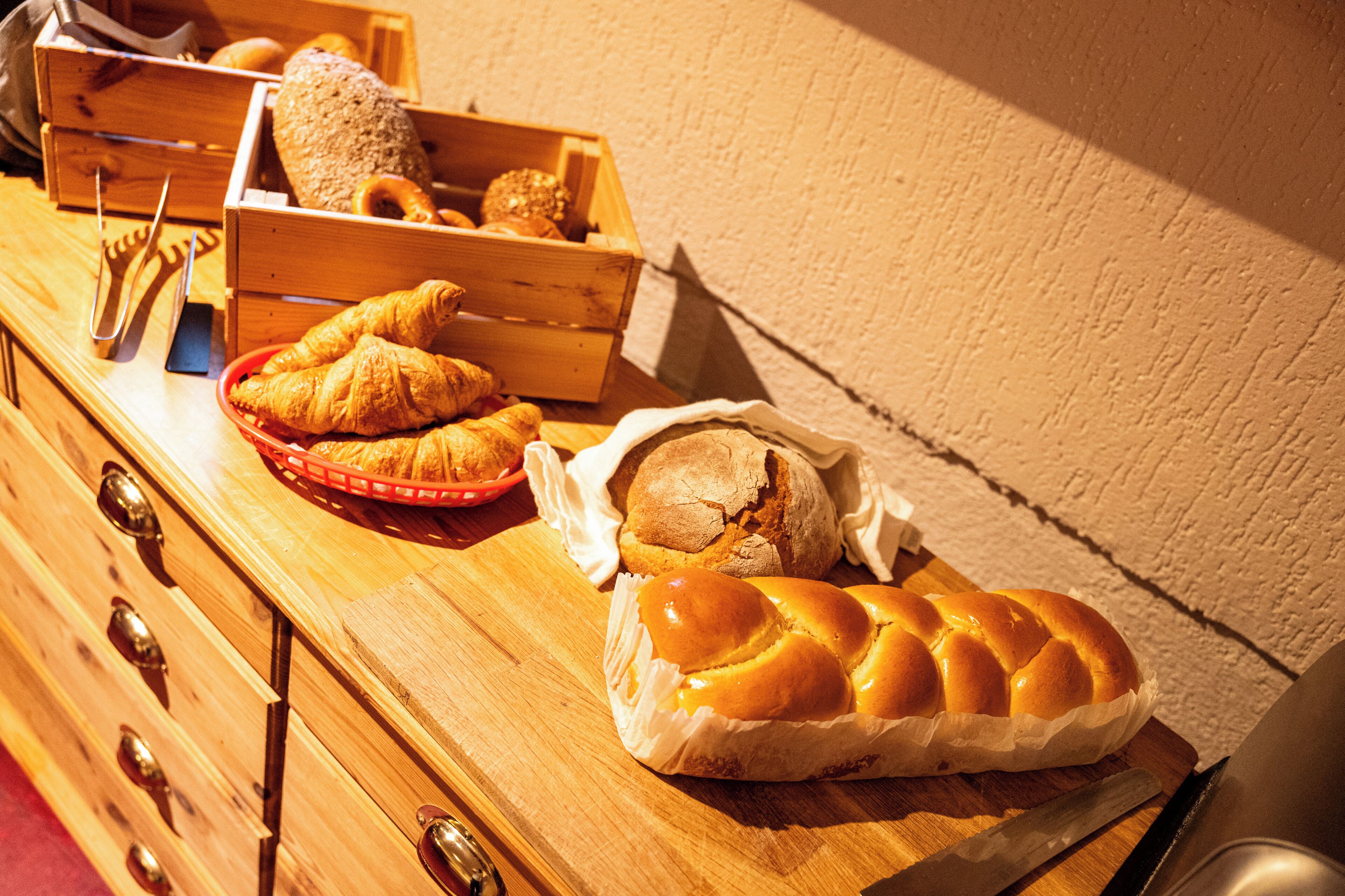 Une table de buffet en bois, sur laquelle sont disposés divers produits de boulangerie, notamment du pain et des viennoiseries.