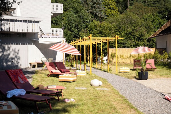 Un jardín con tumbonas, una pérgola y un sendero.