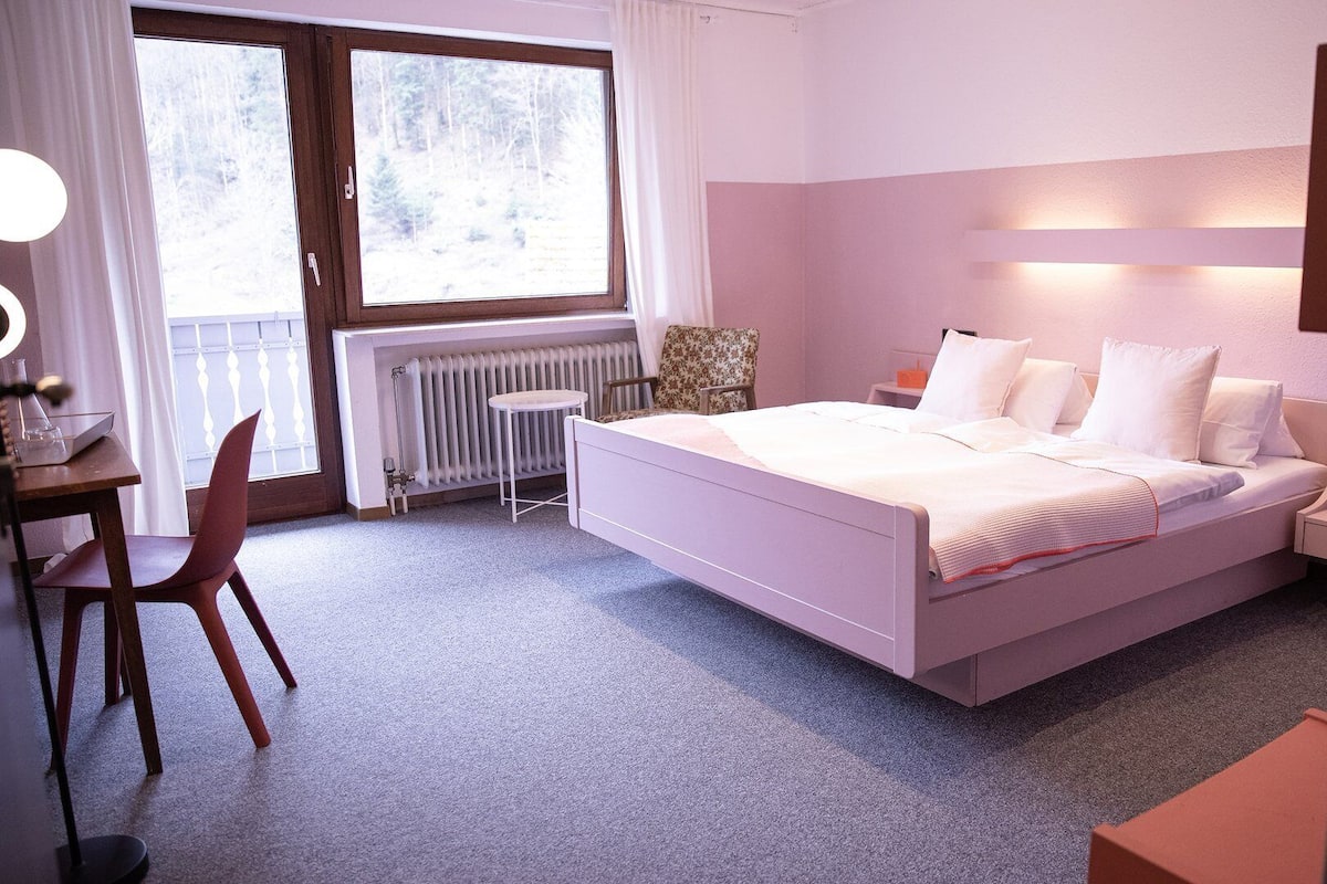 Une chambre à coucher comprenant un lit, un bureau, une chaise, un radiateur et une fenêtre.